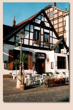 Das historische Fachwerkhaus „Zur Falle“ in der Bückeburger Fußgängerzone, mit Wirtsschild und Sonnenschirmen vor der Tür.